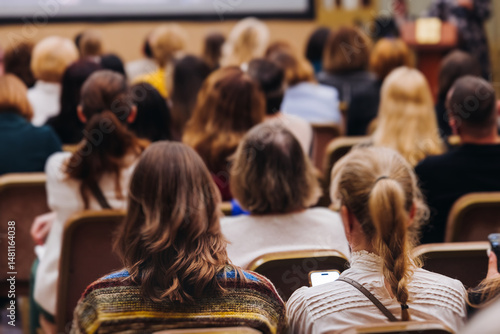 Female audience at the symposyum meeting, participants attendees in conference room hall listens to lecturer, group of women on a medical congress together listen to speaker on a stage at master-class
