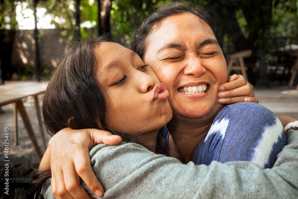 Asian family love and affection between a mother and teenage daughter, hugging one another with happy kiss and amused smile. Warm and close family relationship concept. Asian family love and affection between a mother and teenage daughter, hugging one another with happy kiss and amused smile. Warm and close family relationship concept.