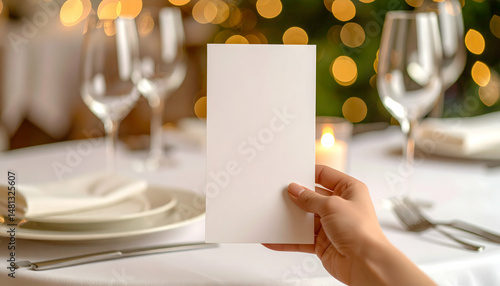 Close Up of Hand Holding a Blank White Menu Card on a Nicely Decorated Dinner Table in Warm Indoor Lighting