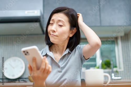 Obraz na plátně ストレスを抱えた表情でスマホを見る女性