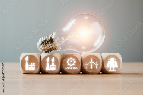 Light bulb with renewable energy icons on wooden blocks, symbolizing smart grid technology and sustainable energy solutions.