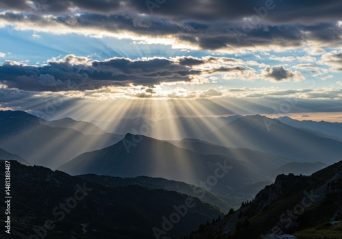 Sun rays over mountain ridges with cloudy sky