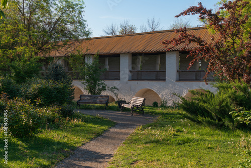Wallpaper Mural A picturesque park with benches on the territory of the Astrakhan Kremlin against the background of a fortress wall with a gallery on a sunny spring day, Astrakhan, Russia Torontodigital.ca