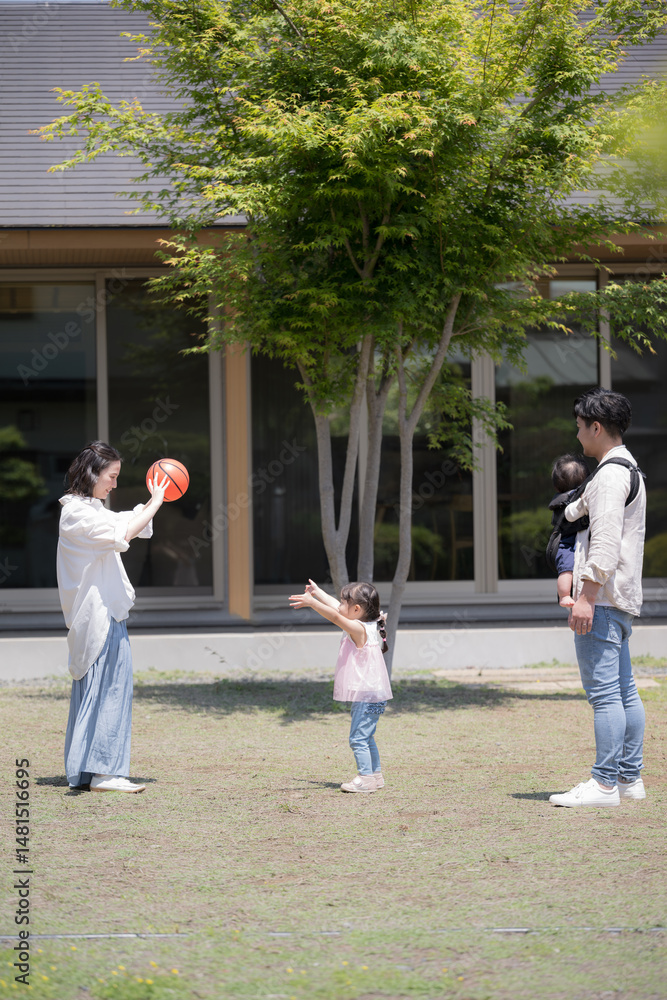 Fototapeta premium 平屋の戸建ての庭の前でボールを投げて遊ぶ家族と子供の幸せの不動産のファミリーイメージ 縦