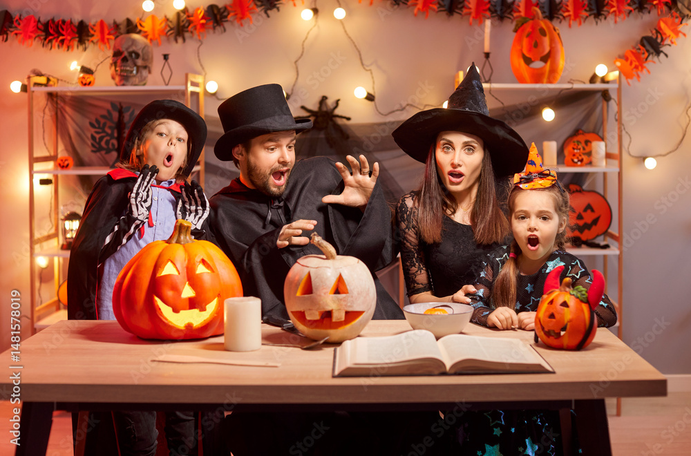 Fototapeta premium Halloween family holiday bewitchery, magical spell, parents, funny kids with pumpkin lantern in scary costumes for dress ups party night event, spooky monster, horror cosplay look, charm, enchantment