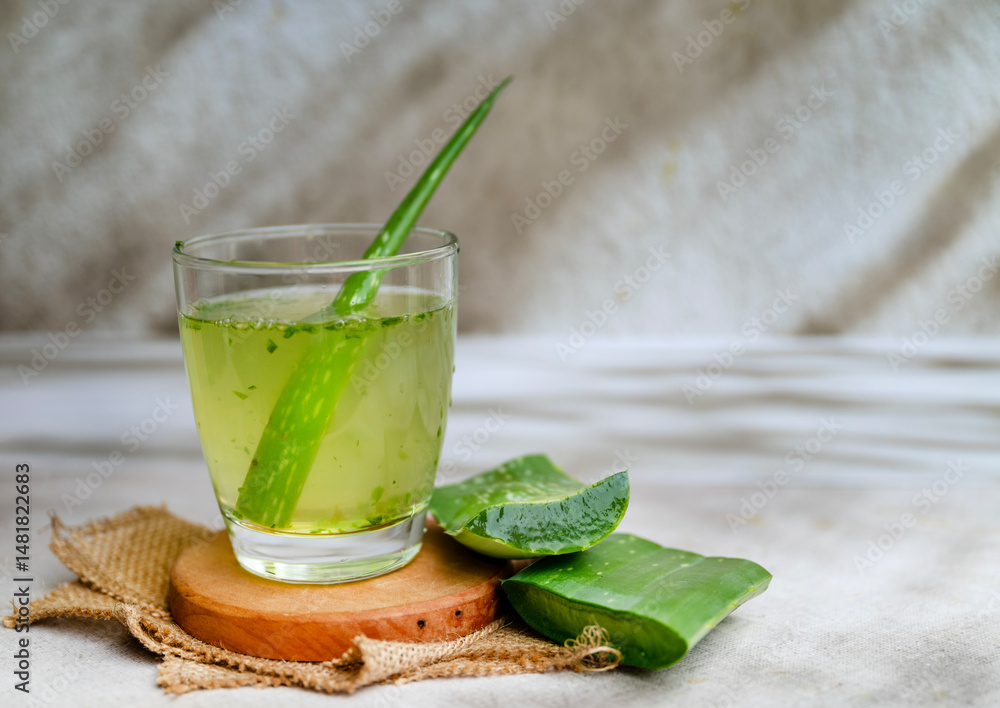Fototapeta premium Fresh aloe vera drink in glass cup with aloe slices 