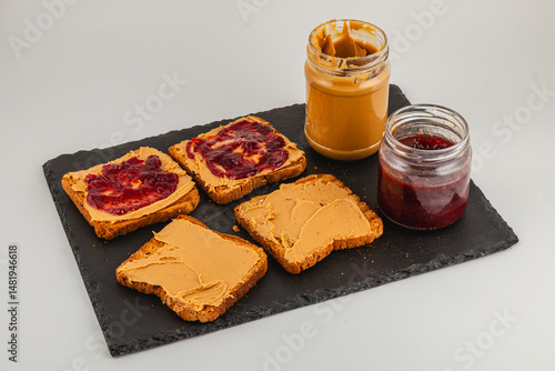 Toasts with peanut butter and jelly on a black serving board