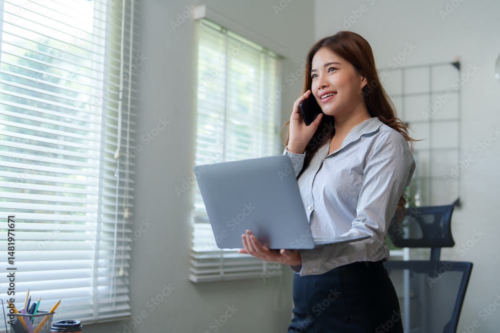 Businesswoman working on laptop and talking on phone in office Businesswoman working on laptop and talking on phone in office
