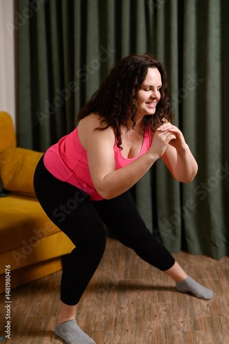 Canvas-taulu Middle aged woman doing squats with side rolls at home, strengthening leg muscles