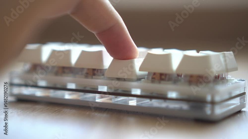 A close-up view of a hand operating a keyboard device.