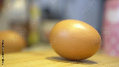 A single, golden-yellow egg on a wooden surface.