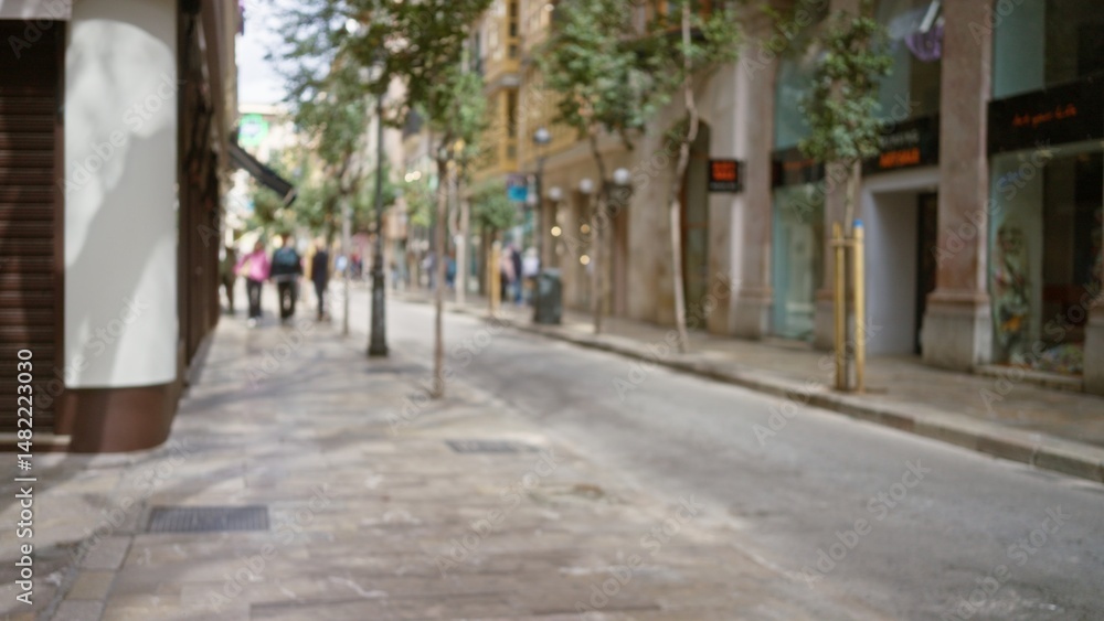 Blurred street scene in a european town with people strolling alongside trees and shops, embodying a serene, urban atmosphere. Blurred street scene in a european town with people strolling alongside trees and shops, embodying a serene, urban atmosphere.