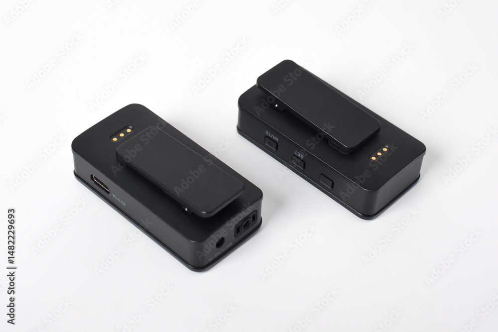 Wireless microphone transmitter and receiver set, black color, compact design with belt clips, isolated on white background Wireless microphone transmitter and receiver set, black color, compact design with belt clips, isolated on white background