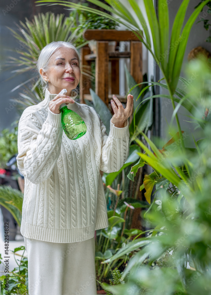 Obraz premium Elderly woman taking care of houseplants
