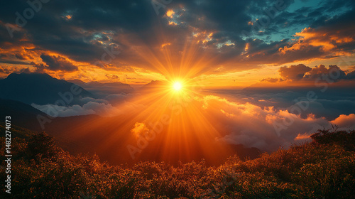 Dramatic sunset over mountain range, sun rays piercing through clouds.