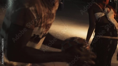Orchestra dancer hitting a traditional tambourine during a night ceremony in Casamance, Senegal — rhythmic moment under event lighting, cultural celebration with music, movement and percussion
