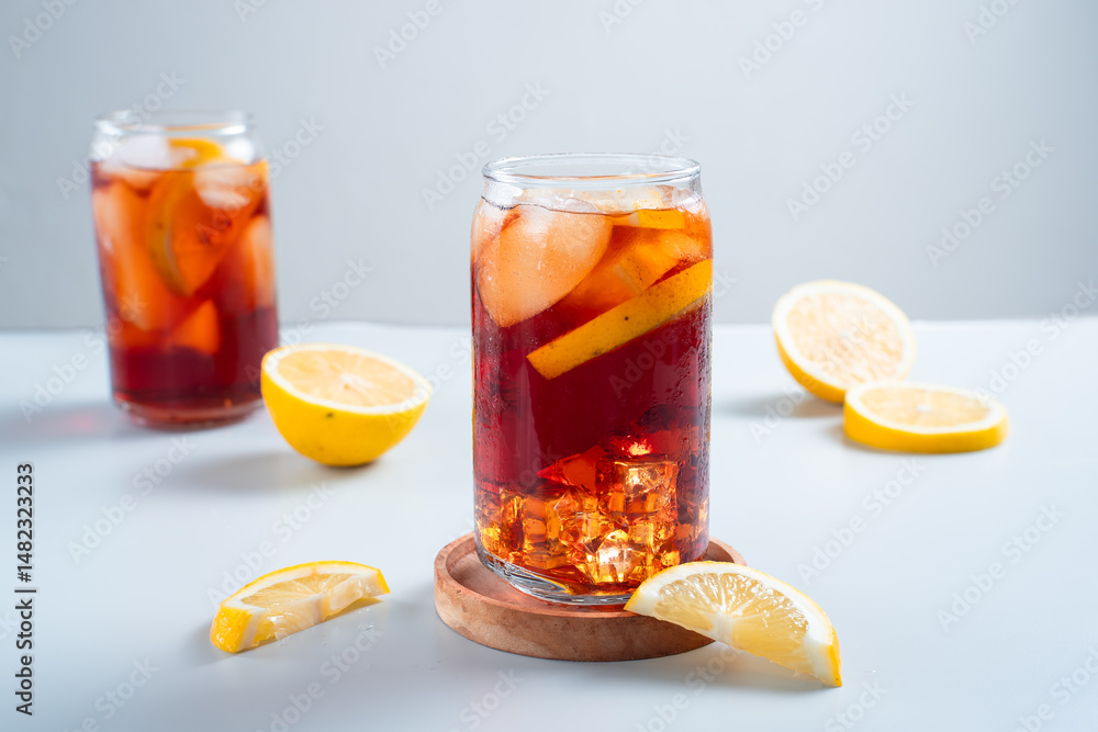 Iced tea with lemon and ice in a tall glass on a white background. The concept of a refreshing drink or lemonade on a hot summer day. Front view and copy space. Iced tea with lemon and ice in a tall glass on a white background. The concept of a refreshing drink or lemonade on a hot summer day. Front view and copy space.