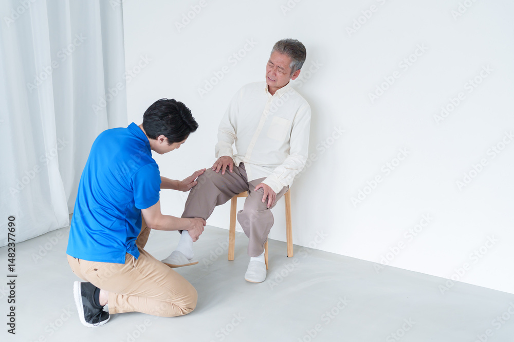 Obraz premium 膝が痛い高齢者男性とスタッフ