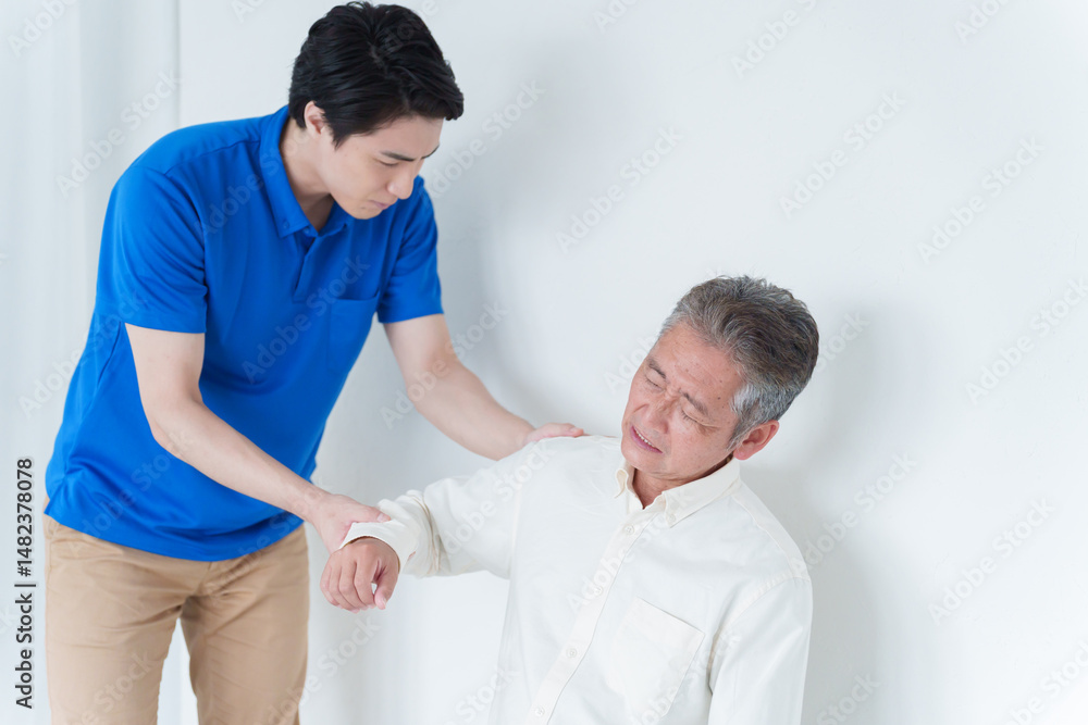 Obraz premium 肩が痛い高齢者男性とスタッフ