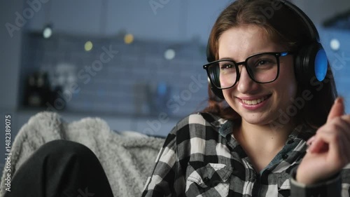 Young Girl Joyfully Listens To Music And Sings Along In The Evening Room, Embracing A Happy Mood