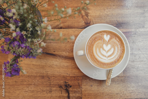 Cup of coffee latte art and flowers on wooden table