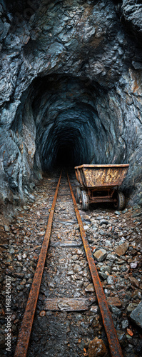 Obraz na płótnie Explore the haunting beauty of an abandoned mine shaft, featuring rusted tracks and a ghostly cart, evoking a sense of history and mystery within the earth's dark corridors. w salonie
