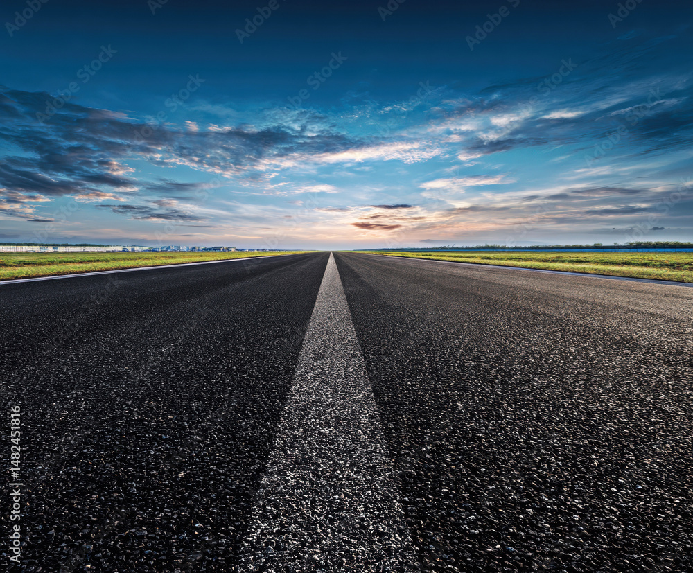 This stunning image captures a wide, empty road stretching towards a vibrant horizon, revealing a breathtaking sky filled with dynamic clouds and hues of blue and orange.
