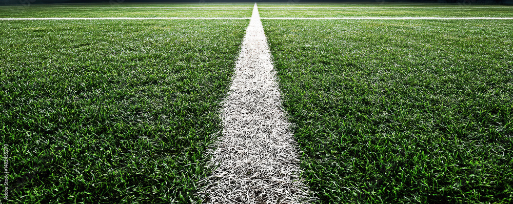 A close-up view of a well-maintained artificial turf field, showcasing the crisp white lines dividing the vibrant green grass, ideal for outdoor sports and recreational activities.