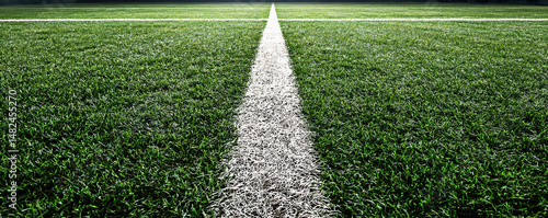 Obraz na płótnie A close-up view of a well-maintained artificial turf field, showcasing the crisp white lines dividing the vibrant green grass, ideal for outdoor sports and recreational activities. w salonie