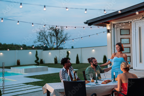 Photography Friends enjoying dinner party in backyard with swimming pool