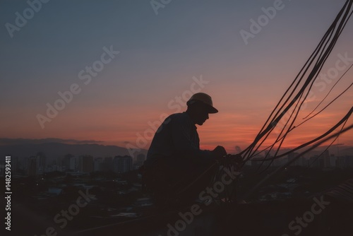 Workers connect power cables against a stunning sunset in an urban setting, showcasing skilled labor and dedication in electrical installations