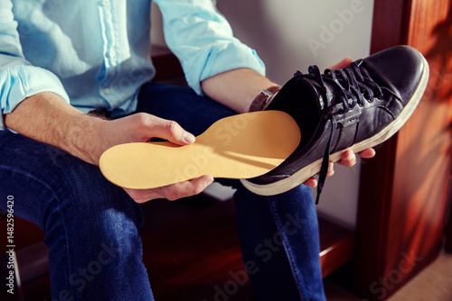 Elegant man holds a leather shoe and puts insole in it