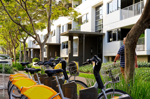 Row of yellow and orange push bikes lined up alongside the road in inner city living