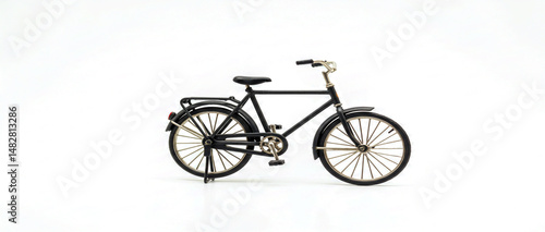 Miniature black bicycle with gold accents displayed on a clean white background for conceptual imagery