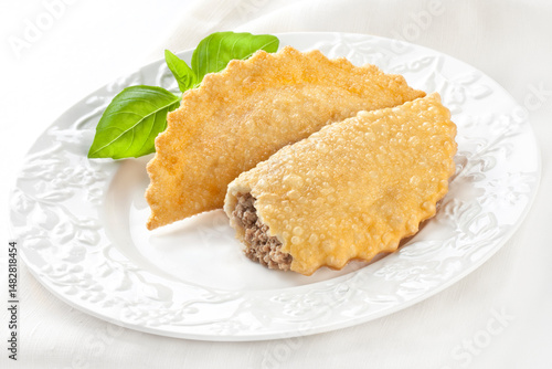 Fried chebureks with meat on a white plate on a white background. Uzbek Tatar cuisine.