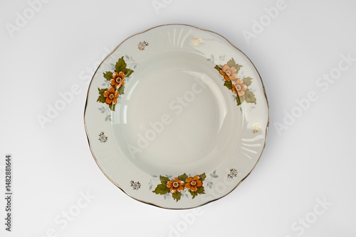 Empty vintage white plate with flowers in plate, isolated on white background. Looking down at a traditional, elegant, white with colorful flower print dinner plate.