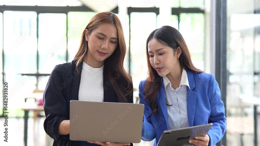 Two businesswomen walking and discussing projects on tablets working together in front of the office. Two businesswomen walking and discussing projects on tablets working together in front of the office.