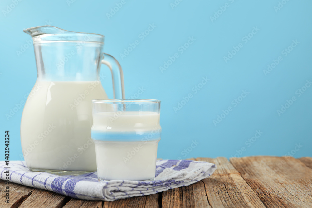 Fresh milk on wooden table against light blue background, closeup. Space for text Fresh milk on wooden table against light blue background, closeup. Space for text