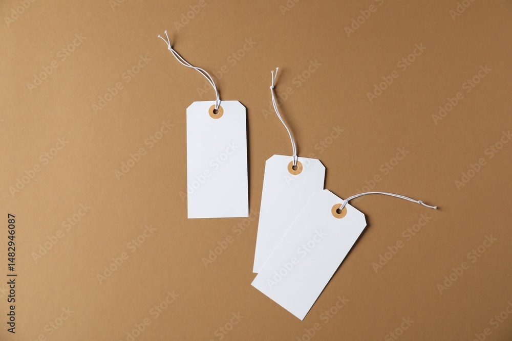 Naklejka premium Blank tags with strings on brown background, flat lay