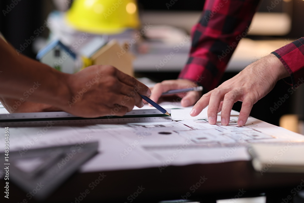 © Wasan - Architect using ruler and pencil reviewing blueprint of architectural project. Two architects are analyzing blueprints for a new building project, using a ruler and pencil to make measurement.
