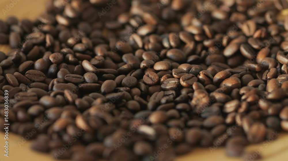 A pile of coffee beans on a table. The beans are of different sizes and shapes. Concept of abundance and variety A pile of coffee beans on a table. The beans are of different sizes and shapes. Concept of abundance and variety