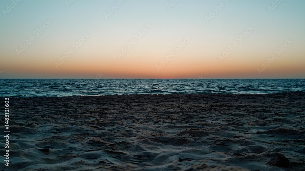 Obraz premium Tranquil Sunset at Ocean Shore with Calm Waves and Warm Sky Colors Reflecting Nature's Beauty