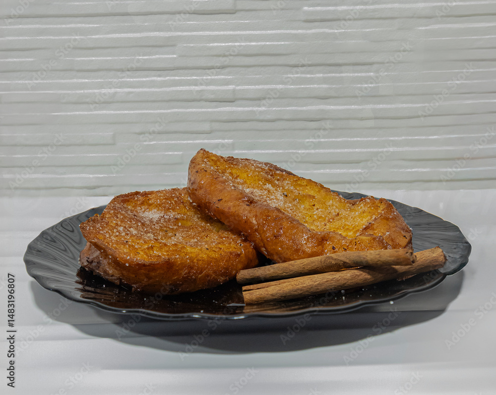 Delicious Torrijas with Sugar and Cinnamon on a Dark Plate Delicious Torrijas with Sugar and Cinnamon on a Dark Plate