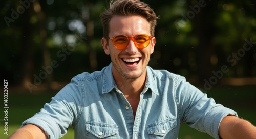 Happy Man Outdoors Smiling Brightly - Joyful man, summer sunshine, orange glasses, denim shirt, outdoor happiness. Represents carefree living, positive energy, and summer vibes