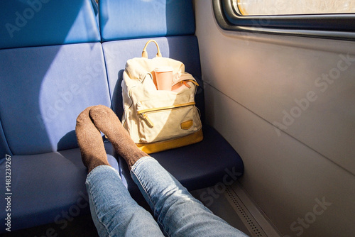 Travelers Enjoy Comfortable Moment Inside a Train Cabin, with Feet Resting on Seat and Backpack Nearby.