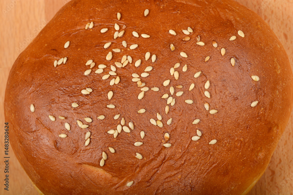 A close-up captures the golden brown, sesame seed-topped surface of a single burger bun