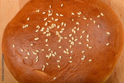 Obraz na płótnie A close-up captures the golden brown, sesame seed-topped surface of a single burger bun w salonie