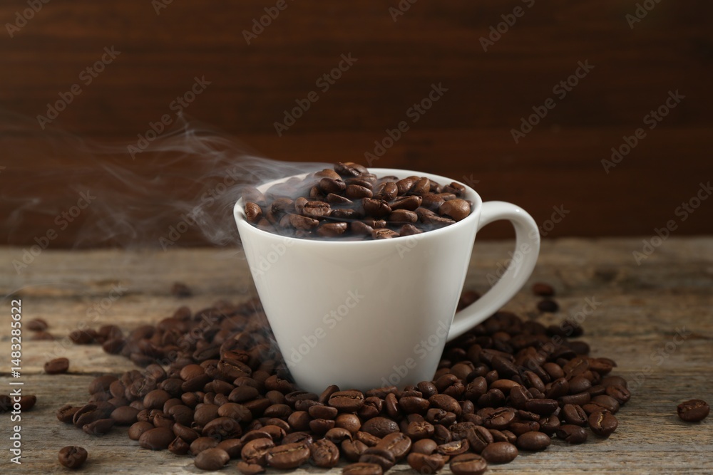 Fototapeta premium Aromatic coffee beans and cup on wooden table, closeup