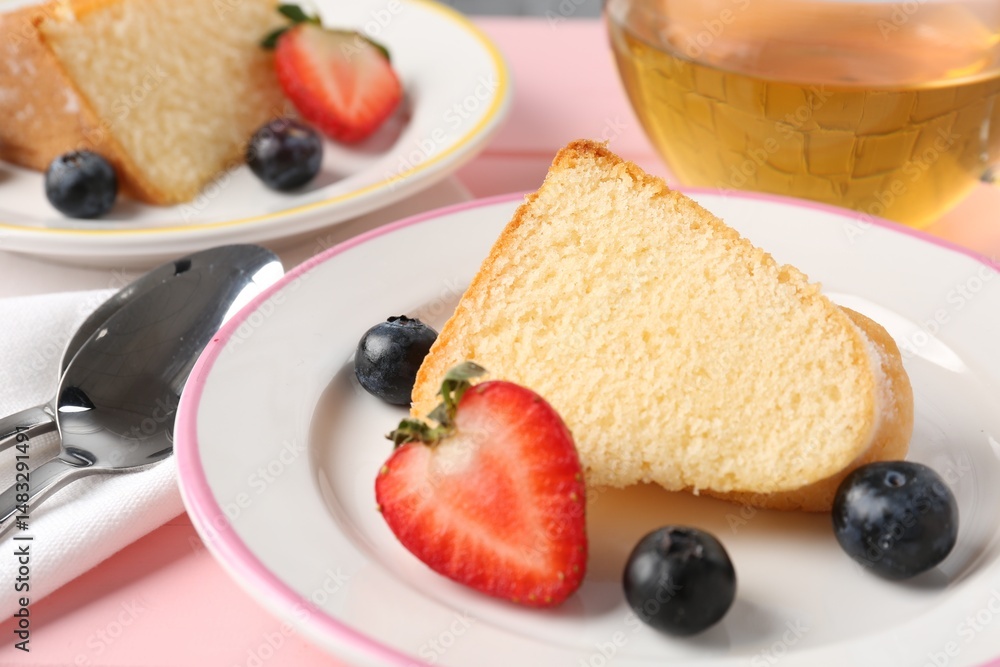 Pieces of tasty bundt cake with berries and tea on pink table, closeup Pieces of tasty bundt cake with berries and tea on pink table, closeup