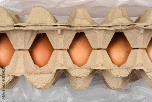 Obraz na płótnie A side view shows brown eggs in a cardboard carton partially covered by a clear plastic bag w salonie